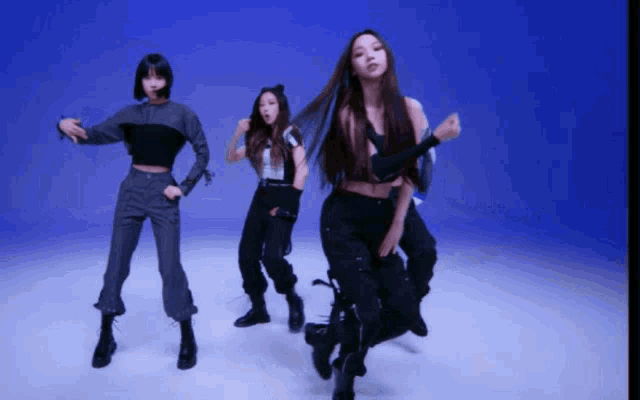 three women are dancing in front of a blue backdrop