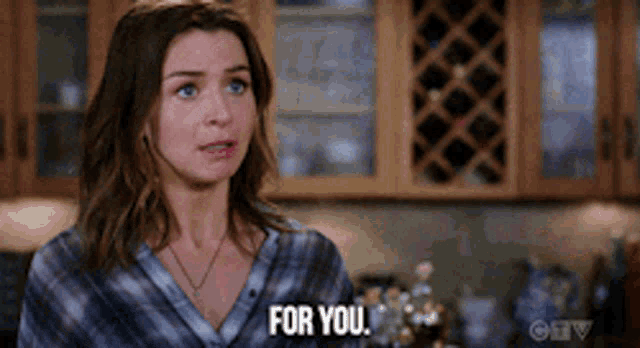 a woman in a plaid shirt says for you in a kitchen