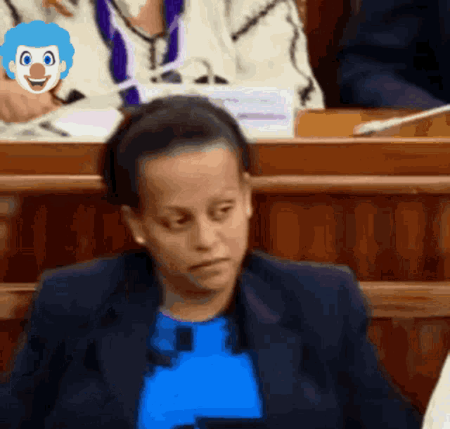 a woman wearing a blue shirt has a clown face on her head