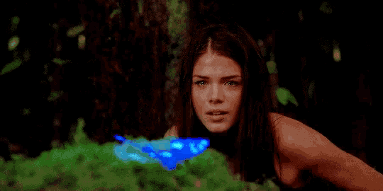 a woman is holding a blue butterfly in her hand