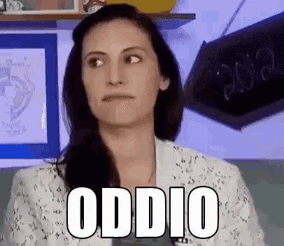 a woman in a white jacket is making a funny face with the word odio written on her face .