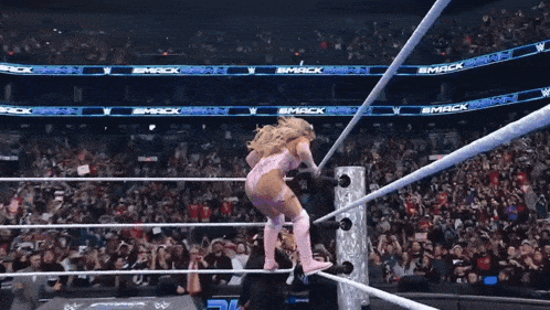 a woman in a pink outfit is standing in a wrestling ring with a banner that says smackdown on it