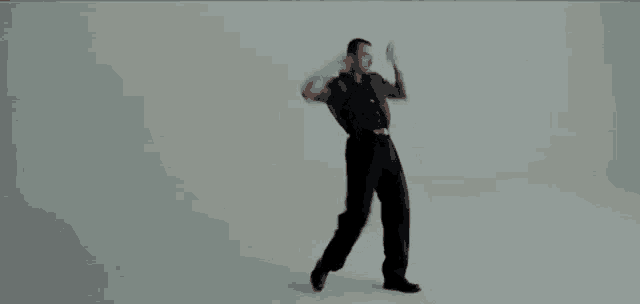 a man in a suit and tie is dancing in a white room .