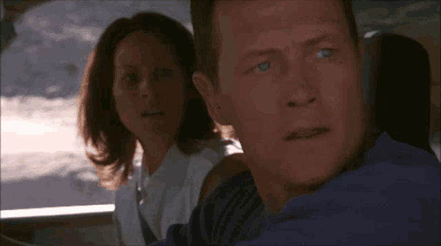 a man and a woman are in a car and the man is looking at the camera