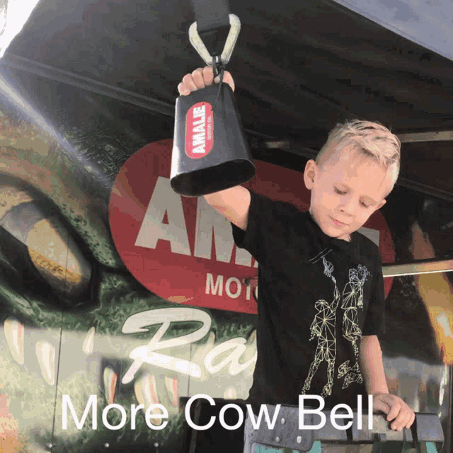 a young boy is holding a cow bell in front of a sign that says ' more cow bell '