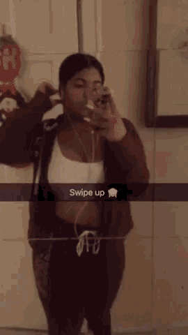 a woman is taking a selfie in front of a mirror with the words swipe up on the bottom .