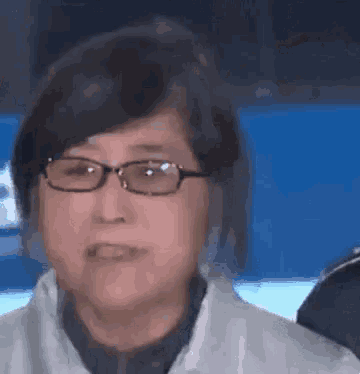 a close up of a woman wearing glasses and a white jacket