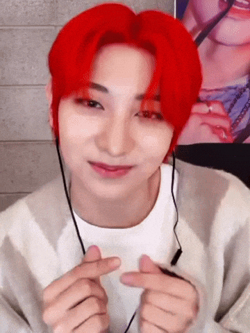 a young man with red hair is making a heart with his hands .