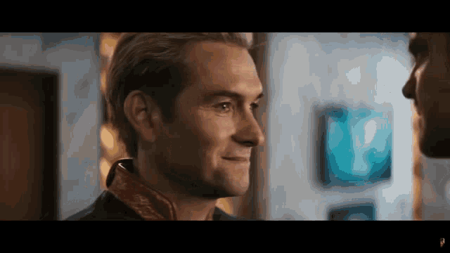a man is smiling at another man in a room .