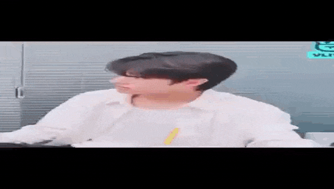 a young man in a white shirt is sitting at a table and looking at the camera .