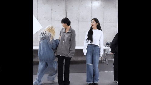a group of people are standing next to each other in a room and laughing .