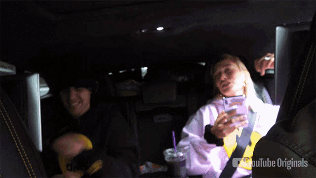 a woman sitting in the back seat of a car with youtube originals on the bottom