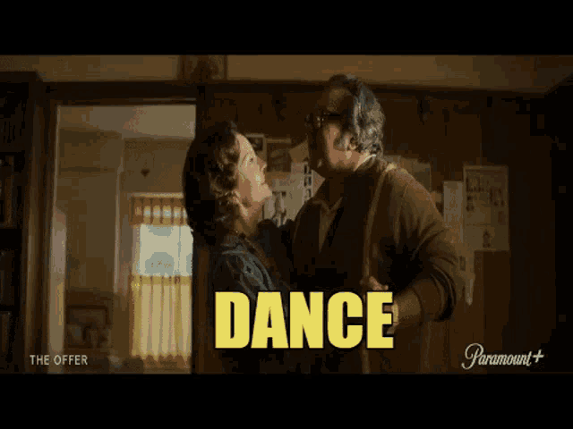a man and a woman are dancing in a living room with the word dance written above them .