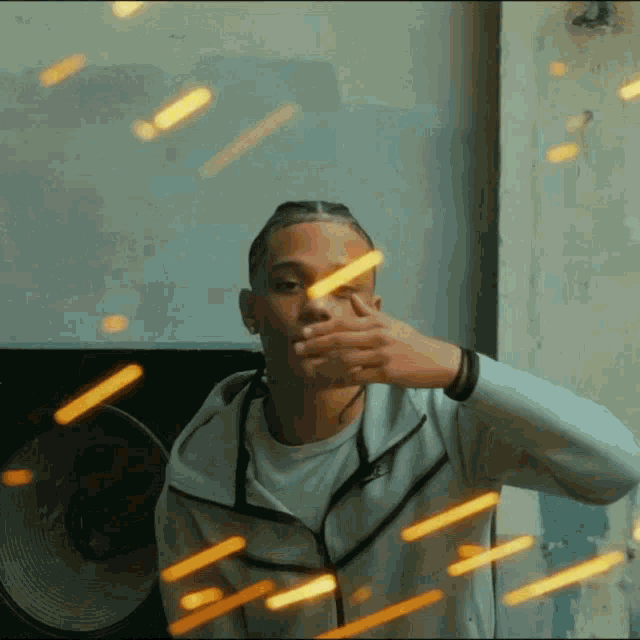 a man wearing a nike jacket is covering his mouth with his hands