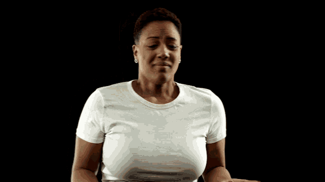 a woman wearing a white t-shirt is making a funny face