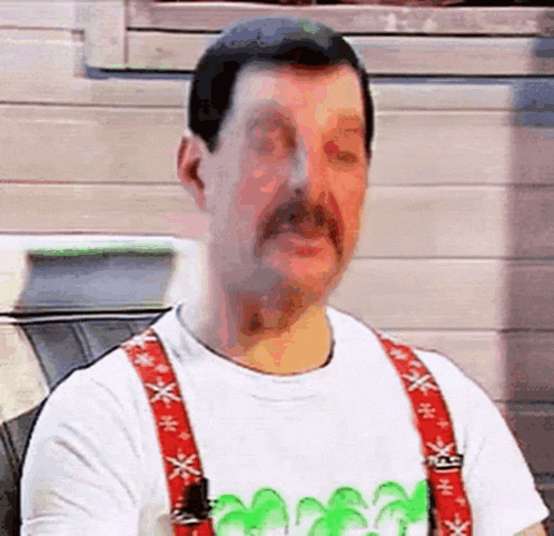 a man with a mustache and suspenders is wearing a white shirt and red suspenders .