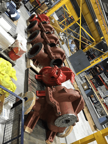 a bunch of red pumps are lined up in a large room