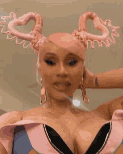cardi b is wearing a pink headband with hearts on it .