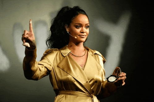 a woman in a gold trench coat is holding a powder and giving a speech