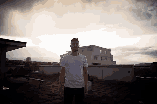 a man in a white t-shirt is standing on a rooftop