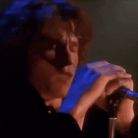 a woman is singing into a microphone in a dark room with blue lights behind her .