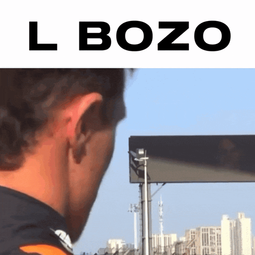 a man stands in front of a billboard with the word bozo above him