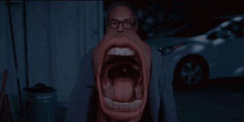 a man with glasses has his mouth wide open and his tongue out
