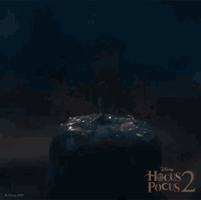 a candle is lit up in front of a poster for disney 's hocus pocus