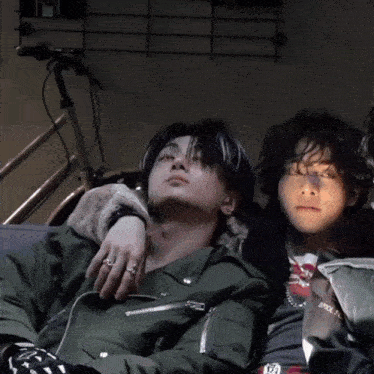 two young men laying next to each other with one wearing a jacket that says ' brooklyn ' on it