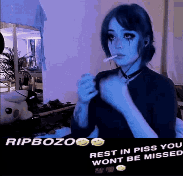 a girl with blue hair is smoking a cigarette and says rip bozo rest in piss you won 't be missed