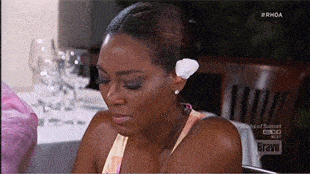 a woman sitting at a table with a bravo logo on the bottom