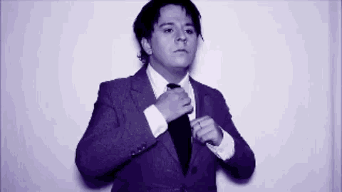 a man in a suit adjusts his tie