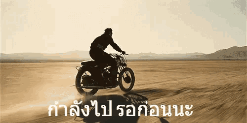 a man is riding a motorcycle in the desert with foreign writing on the bottom right