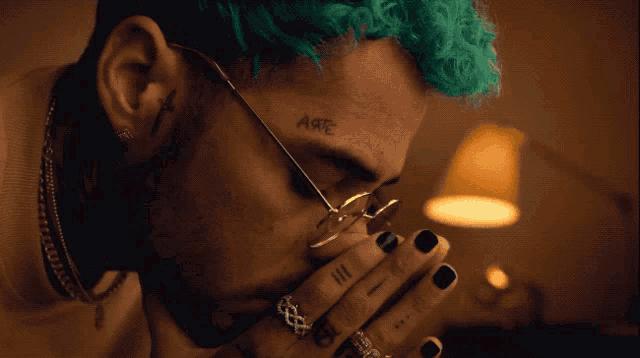 a man with green hair has the word arte tattooed on his forehead