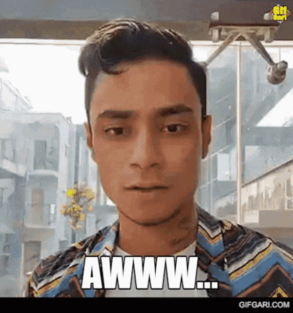a man in a striped shirt is making a funny face and saying awww .