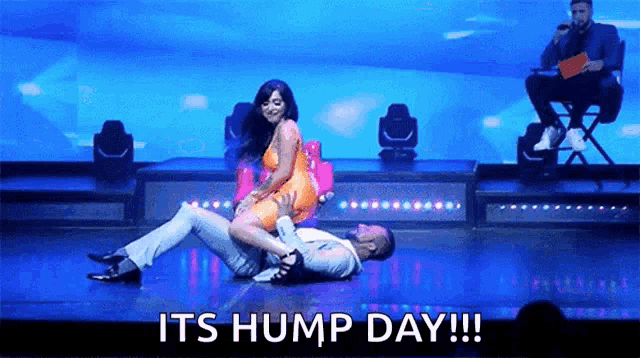 a man and a woman are dancing on a stage with the words its hump day