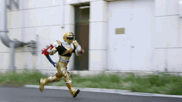 a man in a gold and black superhero costume is running down a street