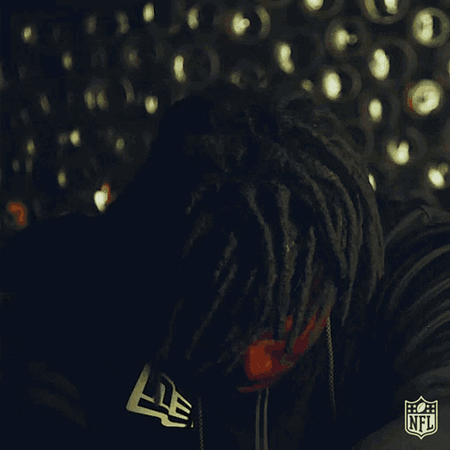 a man with dreadlocks is wearing a black hoodie with the nfl logo on it