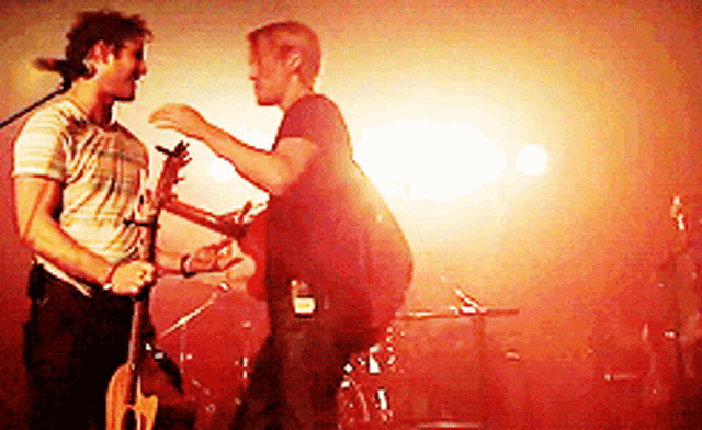a man playing a guitar and another man playing drums on stage