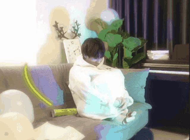 a person is sitting on a couch in front of a clock that shows the time as 3:00