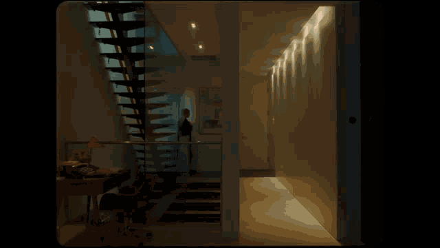 a man in a suit is standing in a hallway next to a staircase
