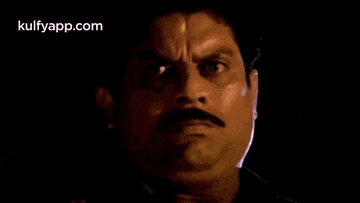 a man with a mustache is looking at the camera with a serious look on his face .