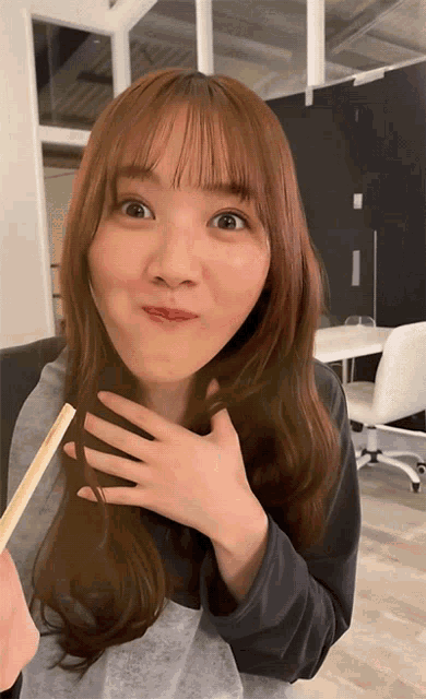 a woman with long brown hair holds a chopstick in her hand