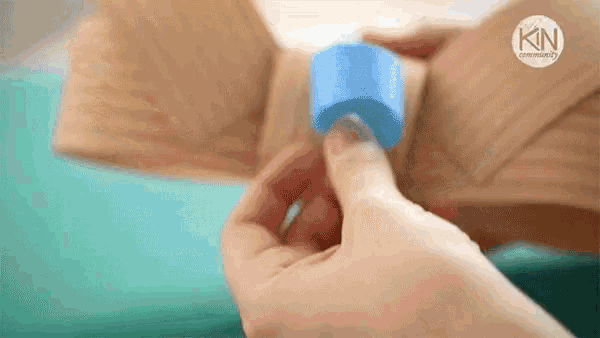 a person is holding a blue object in their hand on a table .