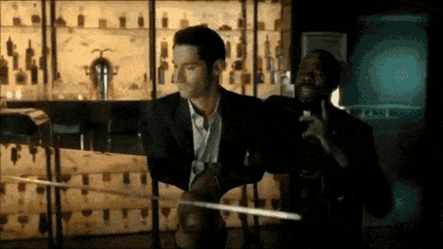 a man in a suit is standing next to another man in a dark room .