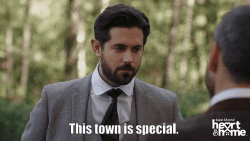 a man in a suit and tie talks to another man and says this town is special