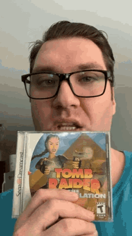 a man wearing glasses is holding a cd that says tomb raider
