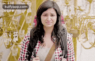 a woman in a plaid shirt is crying in front of a wall .