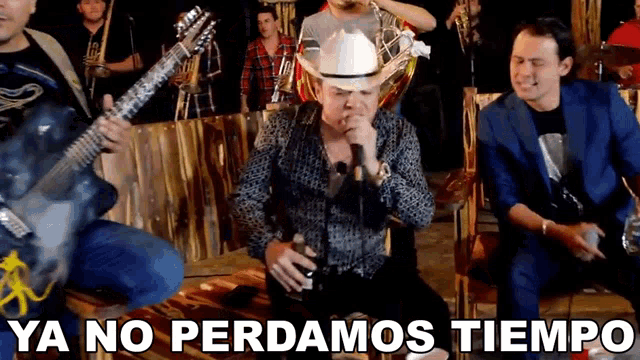 a man in a cowboy hat is playing a guitar and singing into a microphone .
