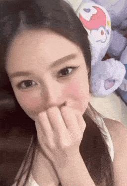 a woman covering her mouth with her hand in front of a stuffed animal
